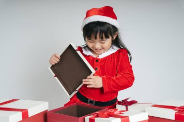 Noel Baba üniformalı, kar festivalini kutlamak için hediye kutulu güzel Asyalı çocuk..