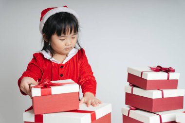 Noel Baba üniformalı, kar festivalini kutlamak için hediye kutulu güzel Asyalı çocuk..