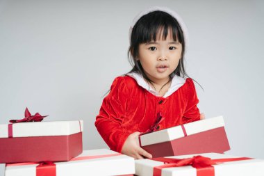 Noel Baba üniformalı, kar festivalini kutlamak için hediye kutulu güzel Asyalı çocuk..