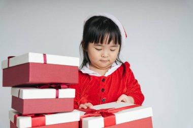 Noel Baba üniformalı, kar festivalini kutlamak için hediye kutulu güzel Asyalı çocuk..