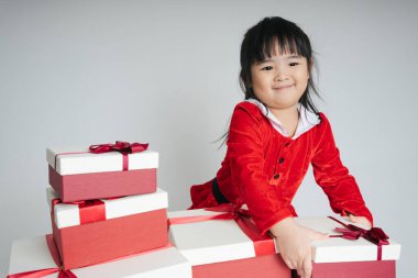 Noel Baba üniformalı, kar festivalini kutlamak için hediye kutulu güzel Asyalı çocuk..