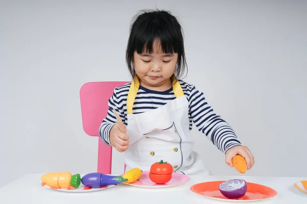 Pretty asian thai kid play role as a chef cooking in kitchen.