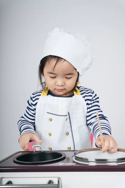 Pretty asian thai kid play role as a chef working at cooker station with boil pot.