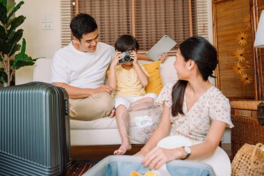 Asyalı aile eşyalarını bavula koyup yola çıkmadan önce hazırlansın..