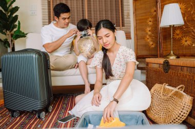 Asyalı aile eşyalarını bavula koyup yola çıkmadan önce hazırlansın..