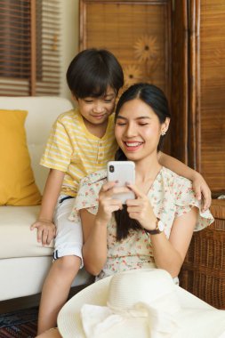 Asyalı anne ve oğlu evde akıllı telefon kullanıyor..