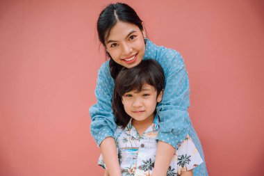 Asyalı Taylandlı anne ve oğlunun yakın plan portresi kırmızı arka planda izole edildi. Anneler Günü.