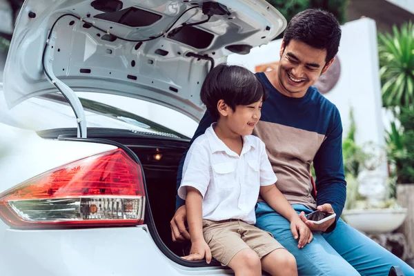 Asian thai father and son sitting at trunk car together.