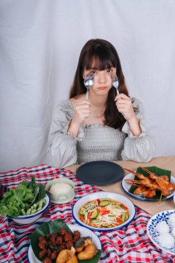 Masada çatal ve kaşıkla yemek yiyen Asyalı kadının portresi..