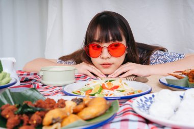 Masadaki Isan yemeğine bakan kırmızı gözlüklü genç Asyalı kadının portresi..