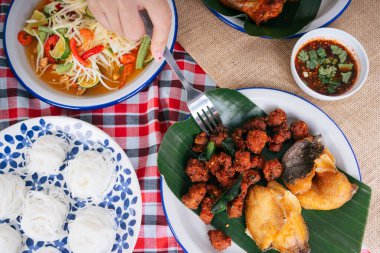 Manzaranın üst kısmında, insanlar bol yağda kızartılmış baharatlı domuz eti ve çatal yiyorlar. Isan gıda konsepti.