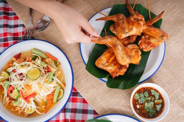 İnsanlar kızarmış tavuk çubuğu ve papaya salatası yiyor. Isan gıda konsepti.