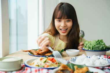 Genç Asyalı kadın portresi evde bir masada Isan yemeği yemekten zevk alıyor..
