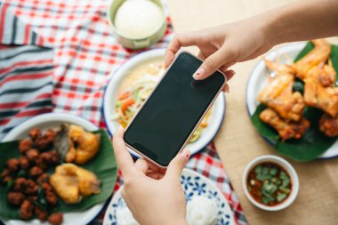 Üst Görünüm - Akıllı telefonlu Isan yemeklerini çeken blog yazarının eli. 
