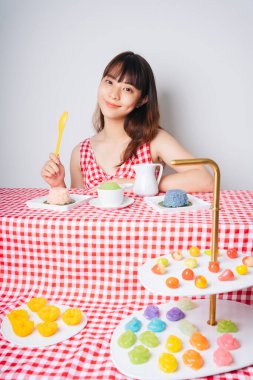 Pembe masadaki birçok pastel Thai tatlısıyla genç Asyalı kadın..