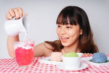 Genç Asyalı kadın tatlı hindistan cevizi sütü döküyor suya kestane tatlısı bardağa.