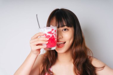 Elinde bir bardak su kestane tatlısı tutan Asyalı bir kadının portresi..