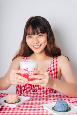 Elinde bir bardak tatlı su kestane tatlısı tutan Asyalı bir kadının portresi..