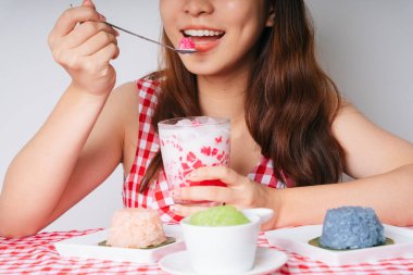 Genç Asyalı kadın kaşıkla su kestane tatlısı yiyor..