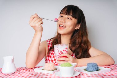 Genç Asyalı kadın kaşıkla su kestane tatlısı yiyor..