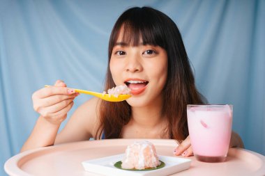 Genç Asyalı kadın kaşıkla tatlı pilav yiyor..