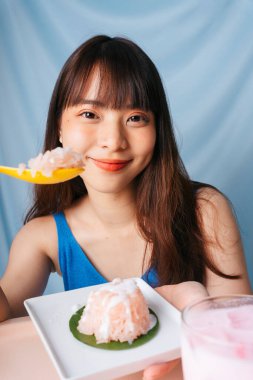 Genç Asyalı kadın kaşıkla tatlı pilav yiyor..