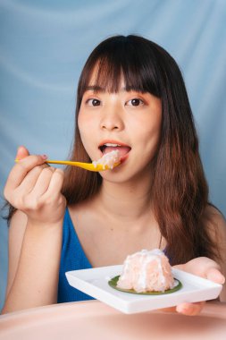 Genç Asyalı kadın kaşıkla tatlı pilav yiyor..