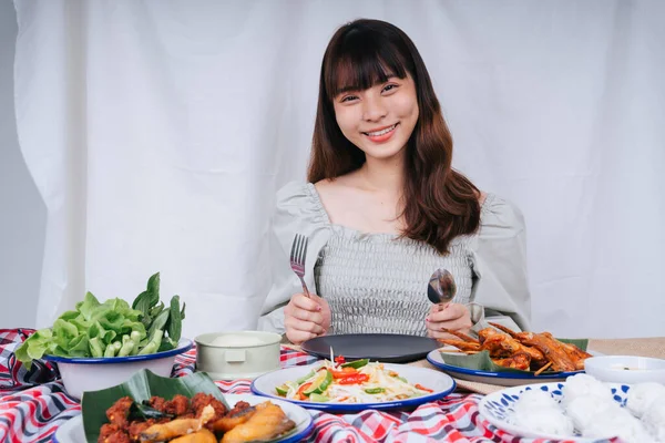 Masada çatal ve kaşıkla yemek yiyen Asyalı kadının portresi..