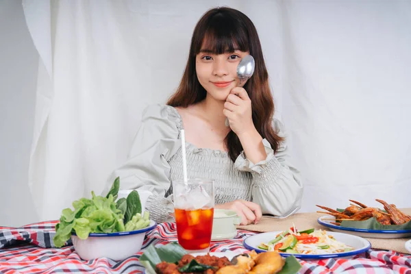 Isan yemeği ve Tayland çayıyla çatal bıçak tutan Asyalı kadının portresi..