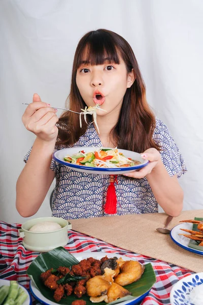 Papaya salatası ve çatallı yemek yiyen Asyalı genç bir kadının portresi..