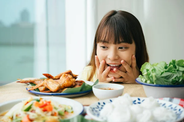 Genç Asyalı kadının portresi. Masadaki Isan yemeğine şaşkın bir ifadeyle bakıyor..