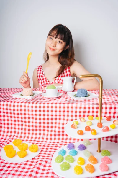 Pembe masadaki birçok pastel Thai tatlısıyla genç Asyalı kadın..