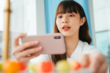 Pastel meyvesi şeklindeki fasulyenin fotoğrafını çeken Asyalı genç kadının yakın portresi..