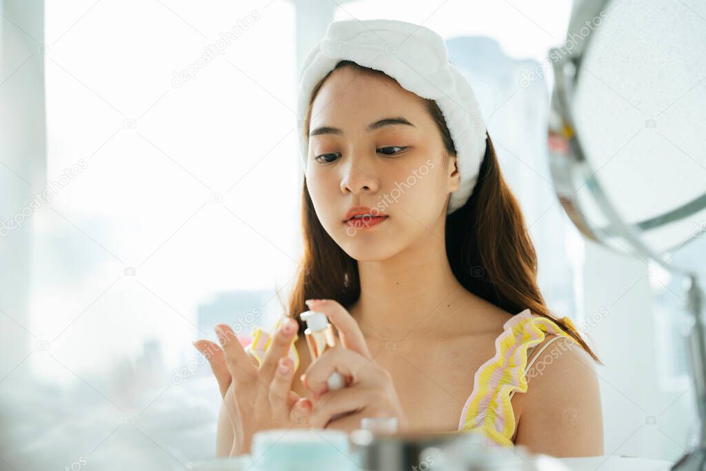Young asian dark hair woman using cosmetic cream on hand.