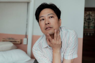 Striptiz tişörtlü Asyalı geyin portresi. Çenesine seksi bir şekilde dokun..