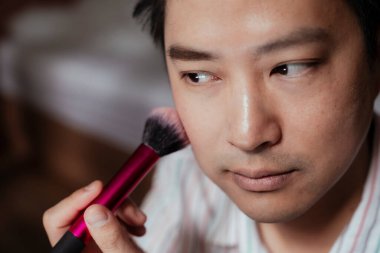 Asyalı eşcinselin önden görünüşü. Yanağını pembe bir allıkla fırçala..