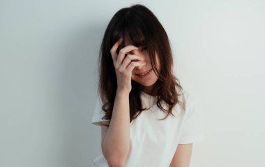 Kıvırcık saçlı kız yarım yüzünü örtecek ve beyaz duvara gülümseyecek..