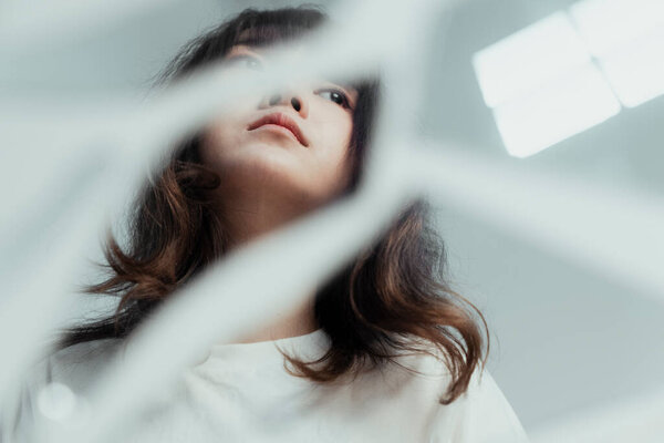Broken mirror on the floor reflect the lonely curly long hair girl looking outside the room.