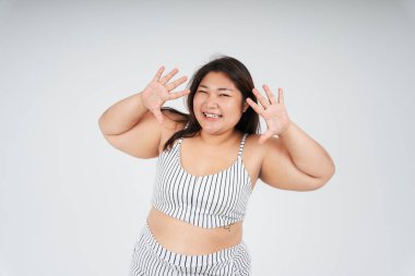 Beyaz arka planda iki elini gösteren neşeli sağlıklı Asyalı tombul kadının portresi..