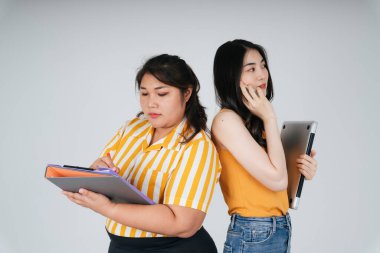 İki Asyalı iş kadını arka arkaya beyaz arka planda dururlar..