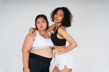 Beyaz arka planda şişman Asyalı ve Afrikalı kadın portresi..