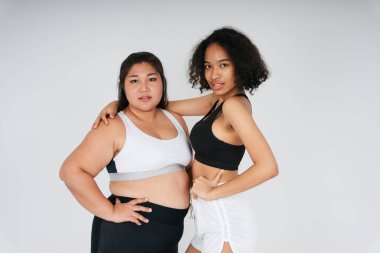 Beyaz arka planda şişman Asyalı ve Afrikalı kadın portresi..