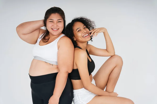 Portrait of diverse women with chubby asian and african woman in sportbra over white background.