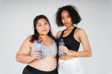 Karışık ırk Afrikalı, Taylandlı ve tombul kadınlar beyaz arka planda su şişesiyle.