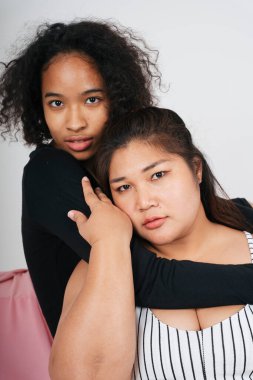 Tombul Asyalı kadın ve beyaz arka planda Afrikalı kıvırcık saçlı kadın..