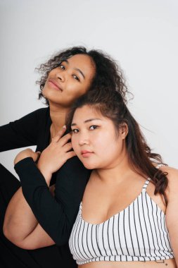 Tombul Asyalı kadın ve beyaz arka planda Afrikalı kıvırcık saçlı kadın..