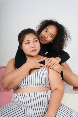 Tombul Asyalı kadın ve beyaz arka planda Afrikalı kıvırcık saçlı kadın..