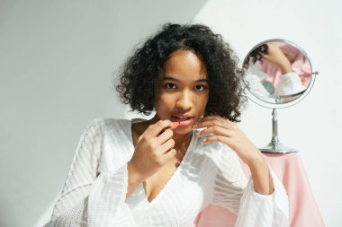 Karışık ırk Afrikalı ve Taylandlı kıvırcık saçlı kadın ruj sürüyor..