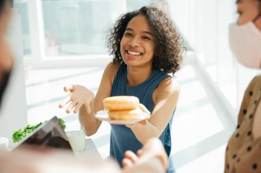 Karışık ırktan Afrikalı ve Taylandlı bir kadın arkadaşıyla donut paylaşıyor..