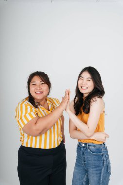 İki Asyalı kadın el çırpıyor ve gülümsüyor..